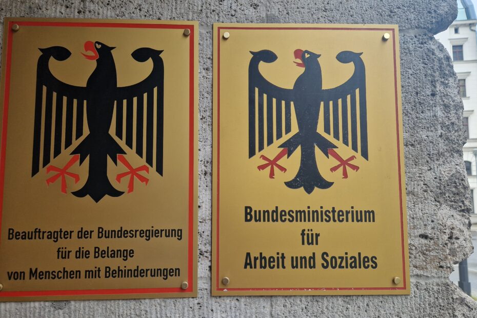 Schilder mit dem Bundesadler am Eingang des BMAS: links: schwarzer Adler auf gelbem Hintergrund mit dem Schriftzug 